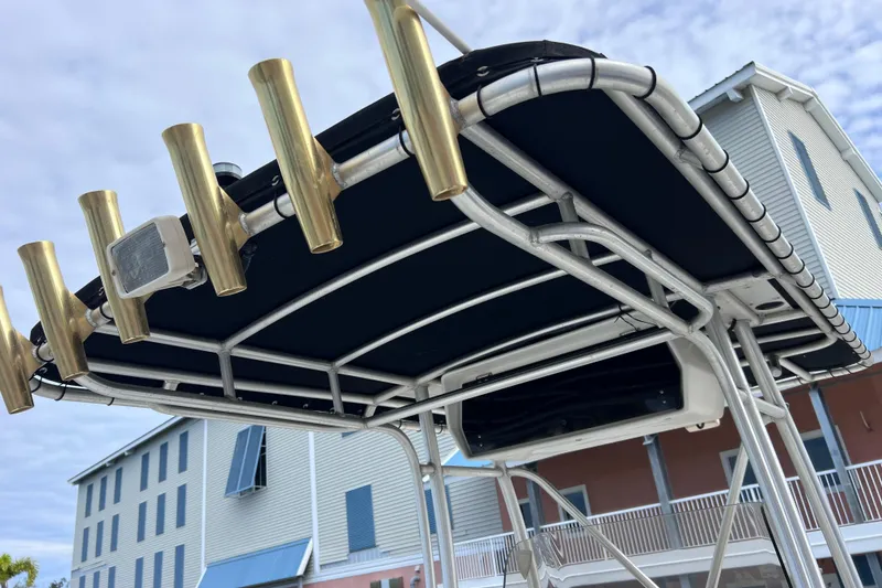 Slide: The Image of T-top of 2003 Wellcraft 29 CCF boat with rod holders, against a building backdrop. - 55