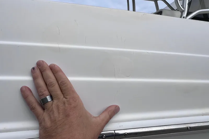 Slide: The Image of Hand touching the side of a 2003 Wellcraft 29 CCF boat, showing surface details. - 58