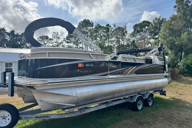 Slide: The Image of 2022 Avalon GS Rear Fish 25' pontoon boat on trailer, parked outdoors. - 25