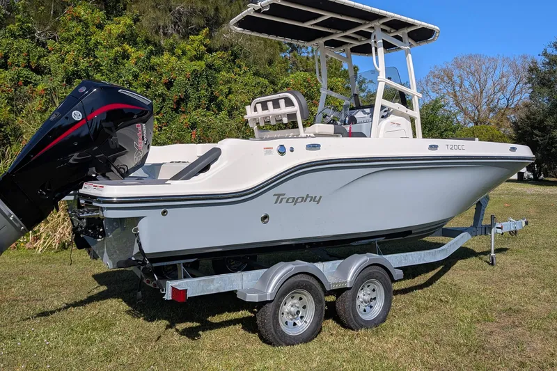 Slide: The Image of 2026 Bayliner Trophy T20CC boat on trailer, parked on grass with trees in background. - 3