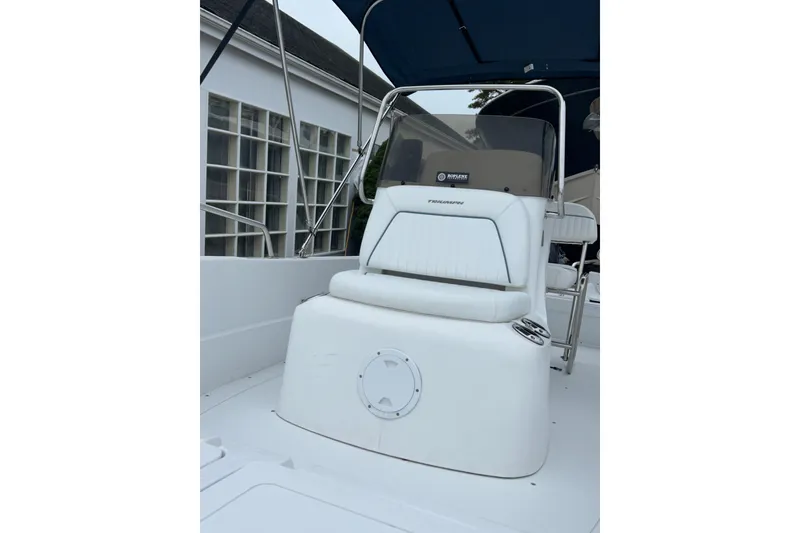 Slide: The Image of 2007 Triumph 170 CC boat with canopy, docked near a building. - 8