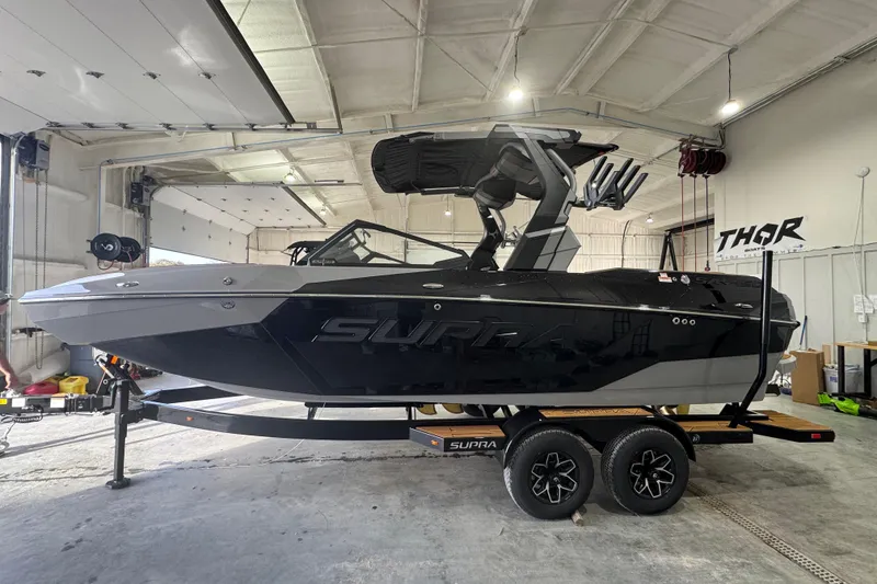 The Image of 2026 Supra SA boat in a garage, sleek black design on a trailer. - 2