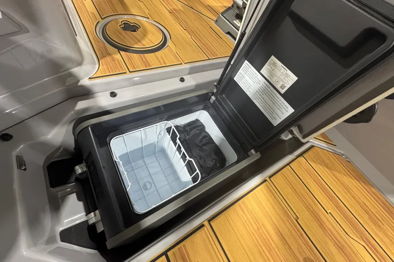 Slide: The Image of 2026 Supra SA boat cooler compartment with open lid on wooden deck. - 28