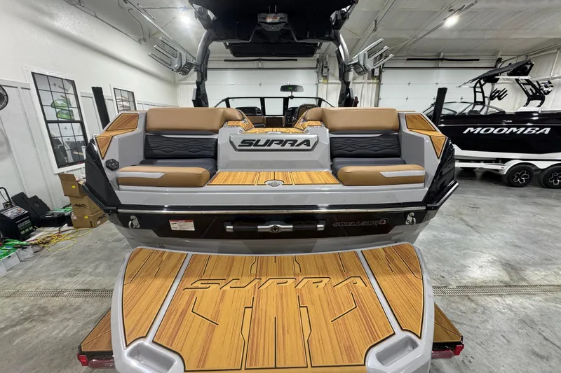 Slide: The Image of 2026 Supra SA boat with teak deck and cushioned seating in a showroom. - 5