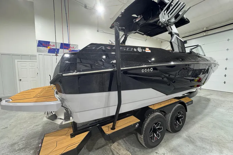 Slide: The Image of 2026 Supra SA boat in showroom, black exterior, dual-axle trailer, wooden deck accents. - 7