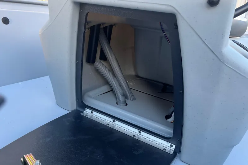 Slide: The Image of Open compartment of 2026 Tracker Bass Tracker Classic CC boat showing interior wiring and hoses. - 75