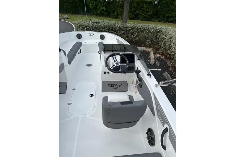 Slide: The Image of 2026 Tahoe T21 boat interior with steering wheel and seating, parked outdoors. - 98