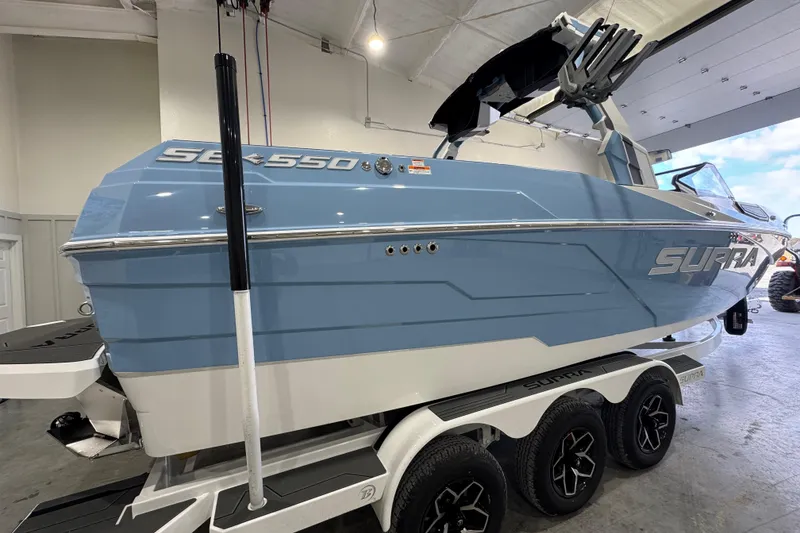 Slide: The Image of 2026 Supra SE boat in showroom, blue and white design, on a trailer. - 7