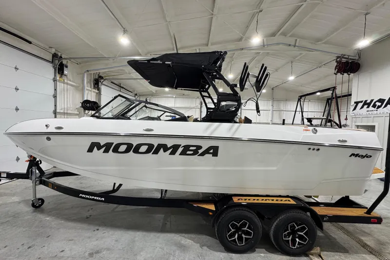 The Image of 2026 Moomba Mojo boat in a garage, on a trailer, with sleek design and black accents. - 1