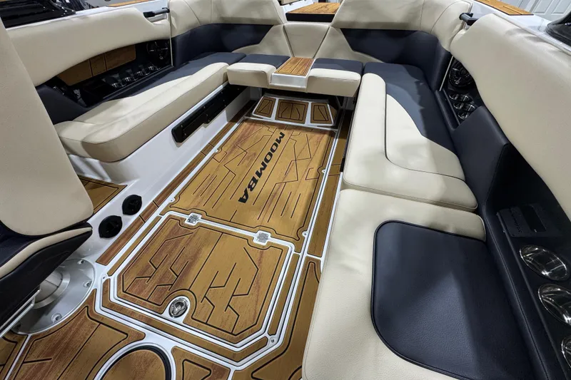 Slide: The Image of 2026 Moomba Mojo boat interior with beige and black seating, wood-patterned flooring. - 13