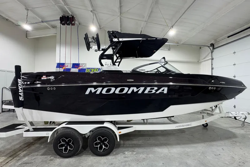 Slide: The Image of 2026 Moomba Max boat in a garage, black exterior, on a white trailer. - 6