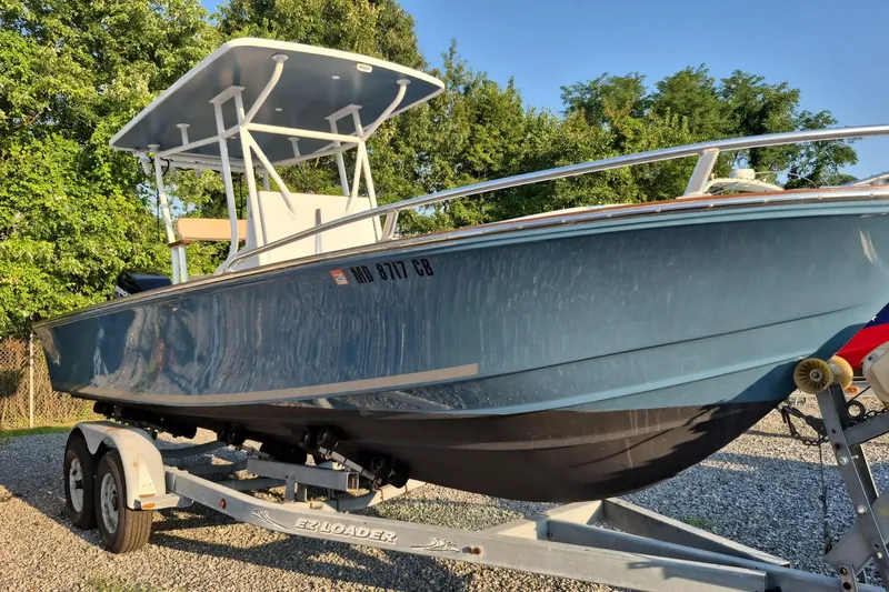 The Image of 1977 Wellcraft 270 Coastal O/B boat on trailer, surrounded by trees. - 0