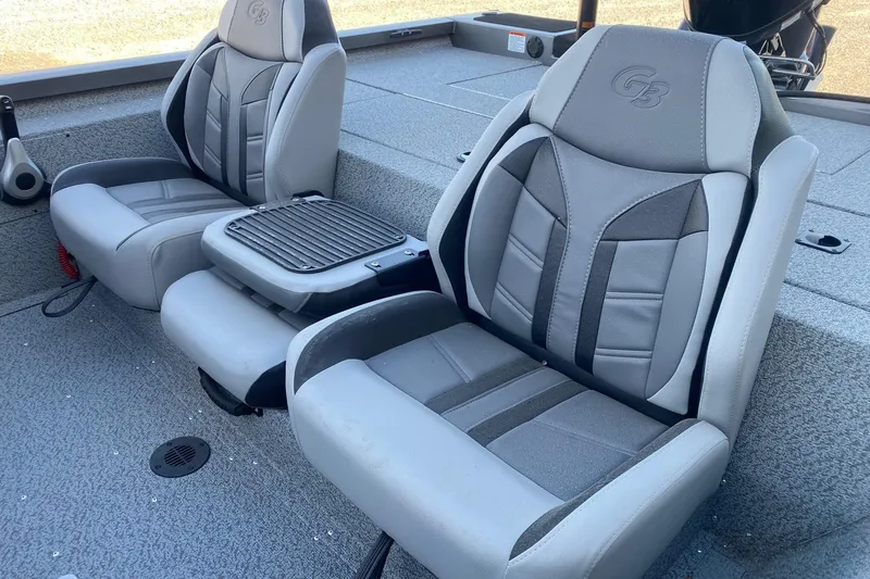 Slide: The Image of 2026 G3 Sportsman 1710 PFX boat seats, gray and black, with armrests and textured flooring. - 10