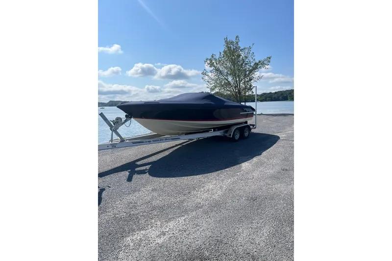 Slide: The Image of 2018 Chris-Craft Launch 23 boat on trailer by a lake under a clear sky. - 3