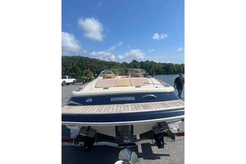Slide: The Image of 2018 Chris-Craft Launch 23 boat on trailer by a lake under blue sky. - 4