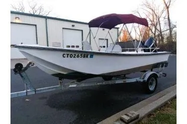 Slide: The Image of 1988 McKee Craft boat on trailer with canopy, parked near industrial building. - 3
