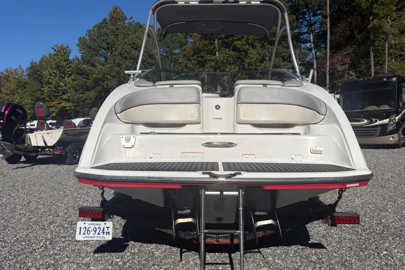 Slide: The Image of 2012 Yamaha Boats AR240 HO rear view, parked on gravel with trees in background. - 2