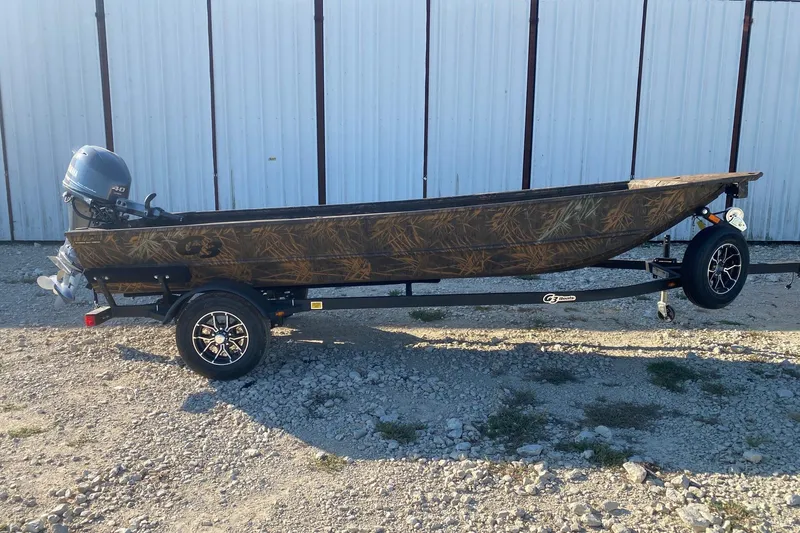 The Image of 2026 G3 Gator Tough 16 DK boat on trailer, camo design, parked outdoors. - 0