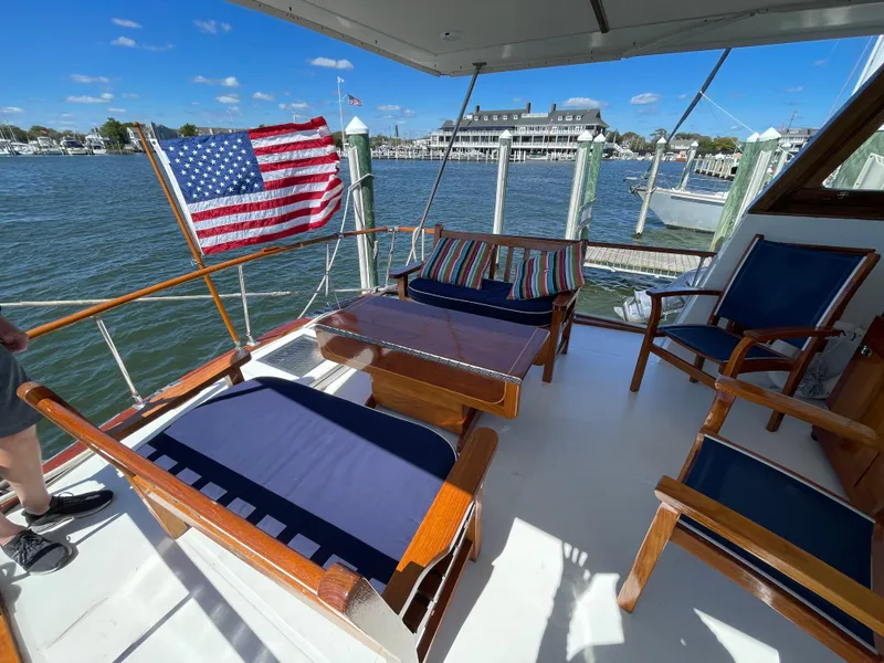 Slide: The Image of 1970 Matthews Flush Deck Cruiser with American flag, docked by a marina under clear skies. - 11