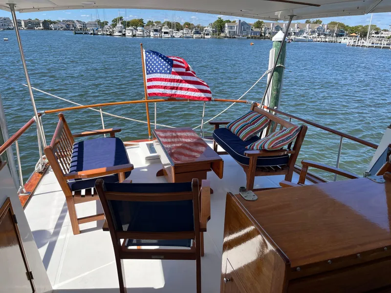 Slide: The Image of 1970 Matthews Flush Deck Cruiser with seating area, American flag, and waterfront view. - 12
