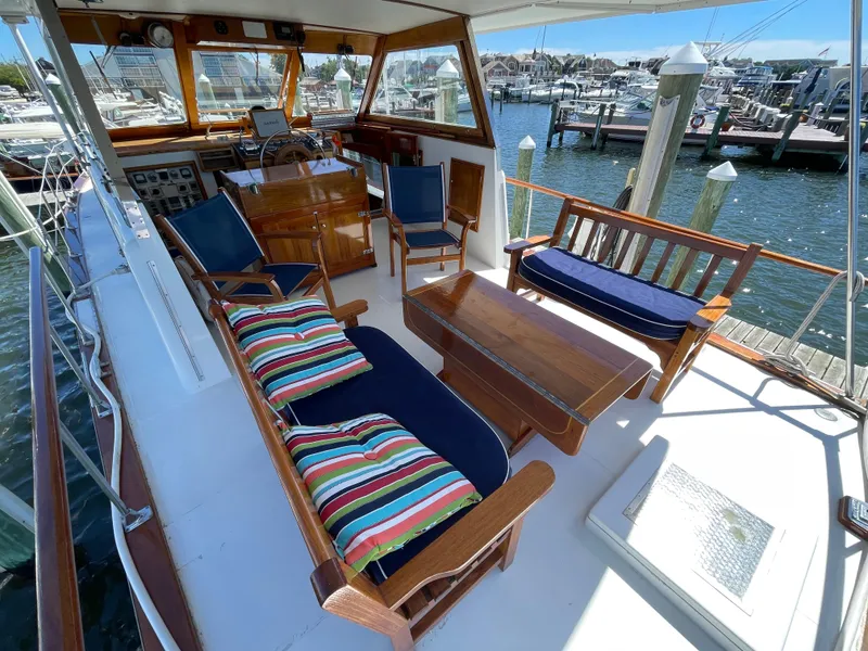 Slide: The Image of 1970 Matthews Flush Deck Cruiser with wooden seating, colorful cushions, and marina view. - 13