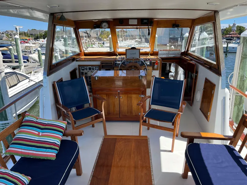 Slide: The Image of 1970 Matthews Flush Deck Cruiser interior with wooden furnishings and blue seating at a marina. - 14