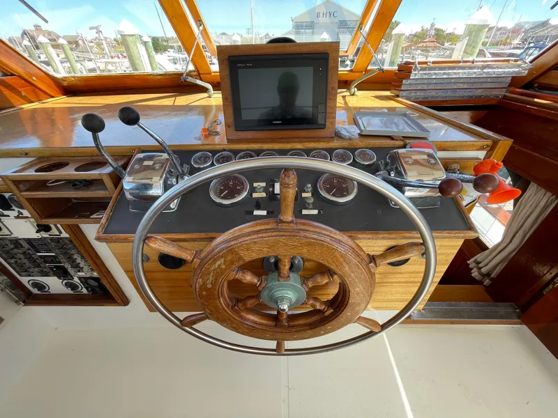 Slide: The Image of 1970 Matthews Flush Deck Cruiser helm with wooden steering wheel and navigation controls. - 16
