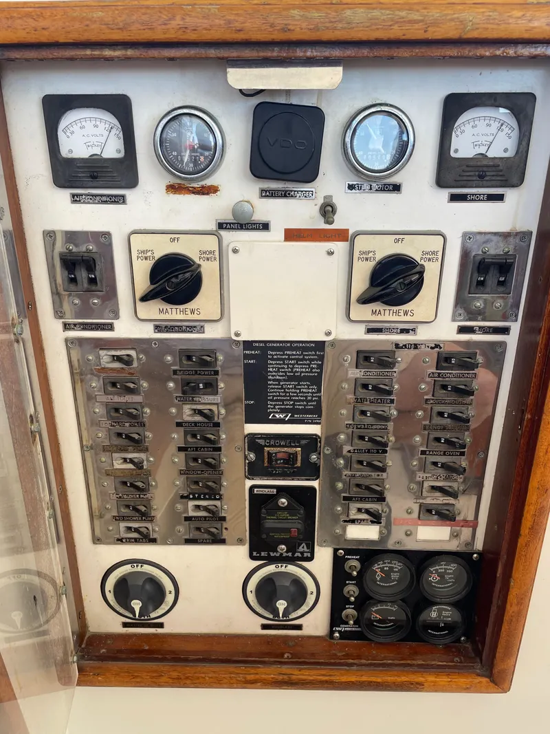 Slide: The Image of 1970 Matthews Flush Deck Cruiser control panel with gauges and switches in a wooden frame. - 17