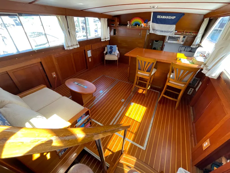 Slide: The Image of 1970 Matthews Flush Deck Cruiser interior with wooden flooring, seating, and nautical decor. - 2