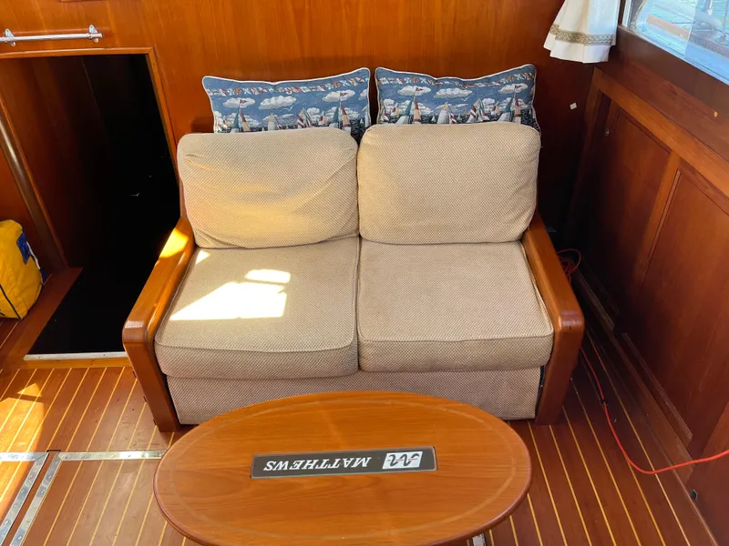 Slide: The Image of 1970 Matthews Flush Deck Cruiser interior with beige sofa and wooden table. - 25