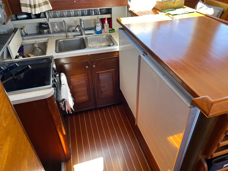 Slide: The Image of 1970 Matthews Flush Deck Cruiser kitchen with wood cabinetry, dual sink, and compact appliances. - 26