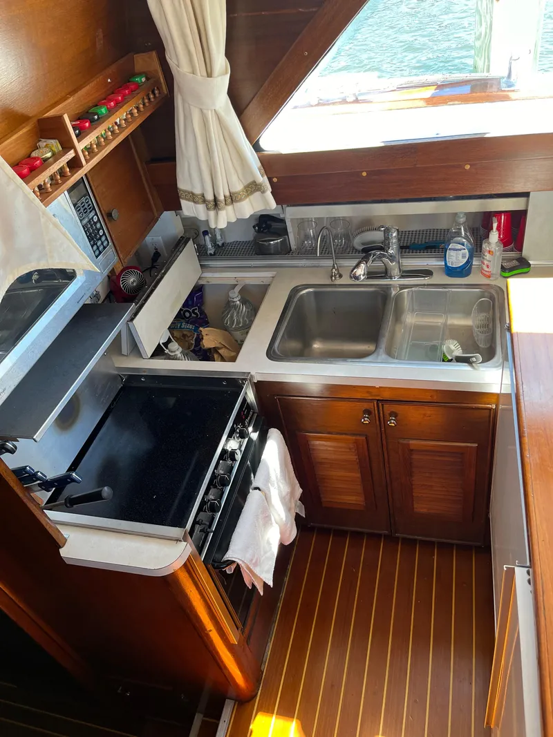 Slide: The Image of 1970 Matthews Flush Deck Cruiser kitchen with stove, sink, wooden cabinets, and nautical decor. - 27