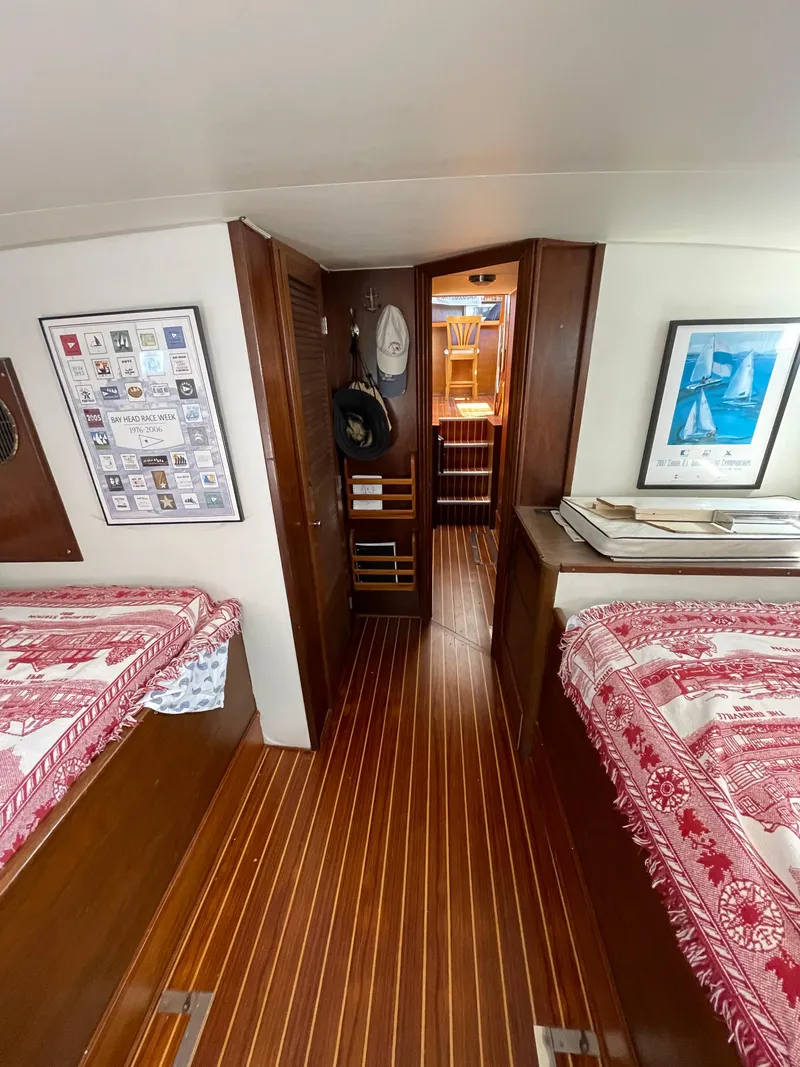 Slide: The Image of 1970 Matthews Flush Deck Cruiser interior with wood flooring and red-patterned bedding. - 28