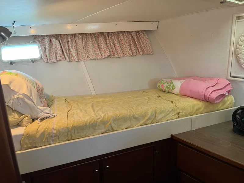 Slide: The Image of 1970 Matthews Flush Deck Cruiser cabin with bed, floral curtains, and wooden storage. - 34