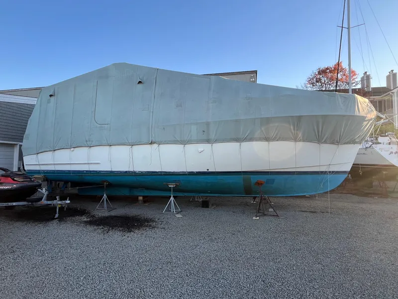 Slide: The Image of 1970 Matthews Flush Deck Cruiser covered, stored on gravel lot. - 45
