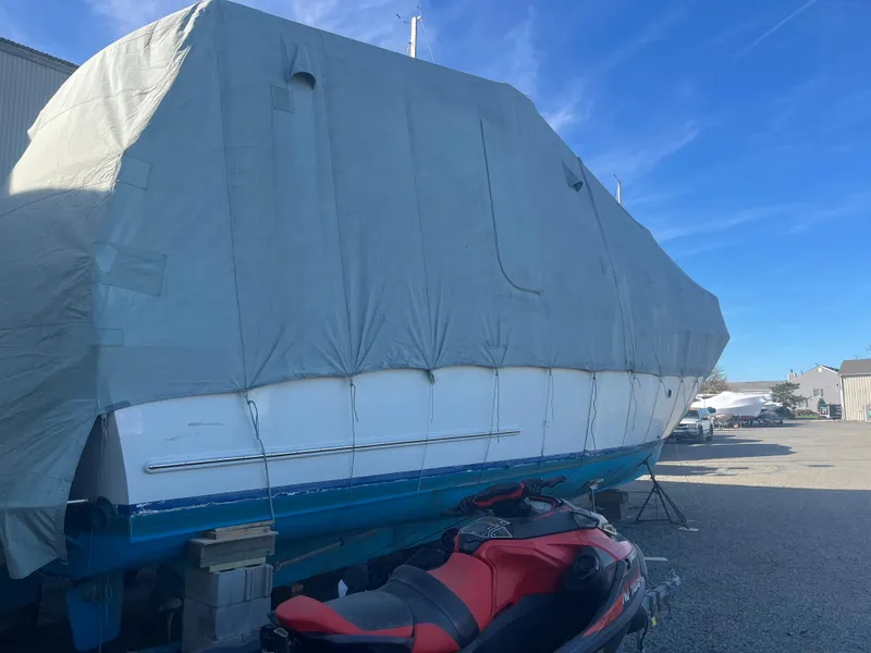 Slide: The Image of 1970 Matthews Flush Deck Cruiser covered, parked outdoors under blue sky. - 46