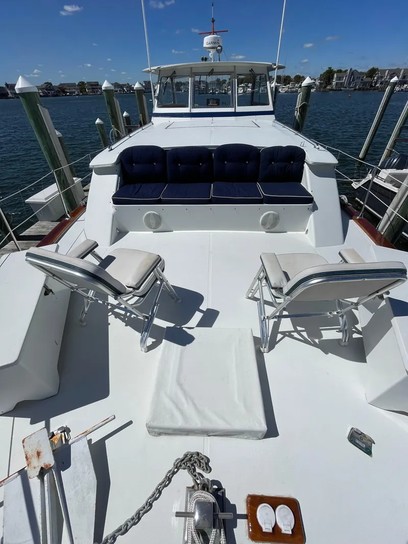Slide: The Image of 1970 Matthews Flush Deck Cruiser with spacious deck and seating, docked by the water. - 6