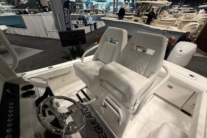 Slide: The Image of 2026 Regulator 23 boat interior with white seating and steering wheel at a boat show. - 11