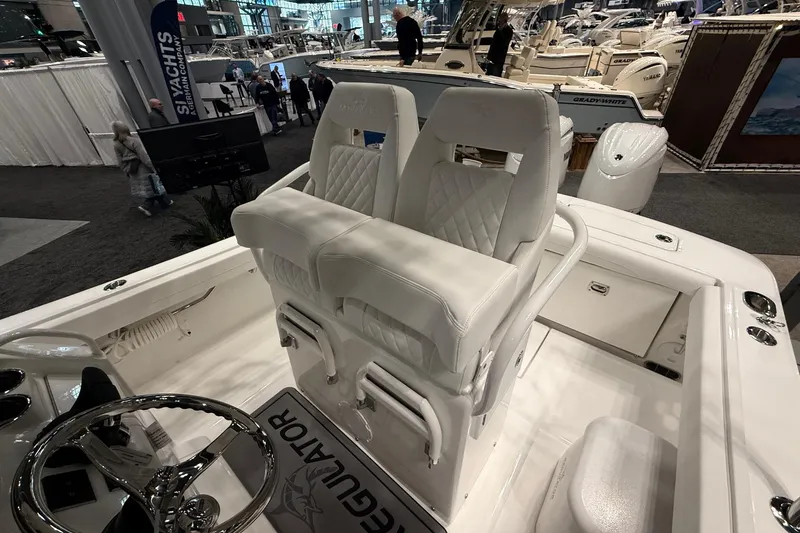Slide: The Image of 2026 Regulator 23 boat interior with white seating and steering wheel at a boat show. - 22