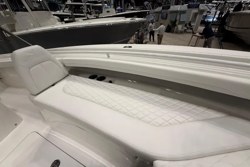 Slide: The Image of 2026 Regulator 23 boat interior with white quilted seating at a boat show. - 32
