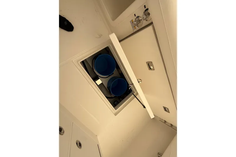 Slide: The Image of 2026 Regulator 23 boat storage compartment with blue containers and secure latch. - 49
