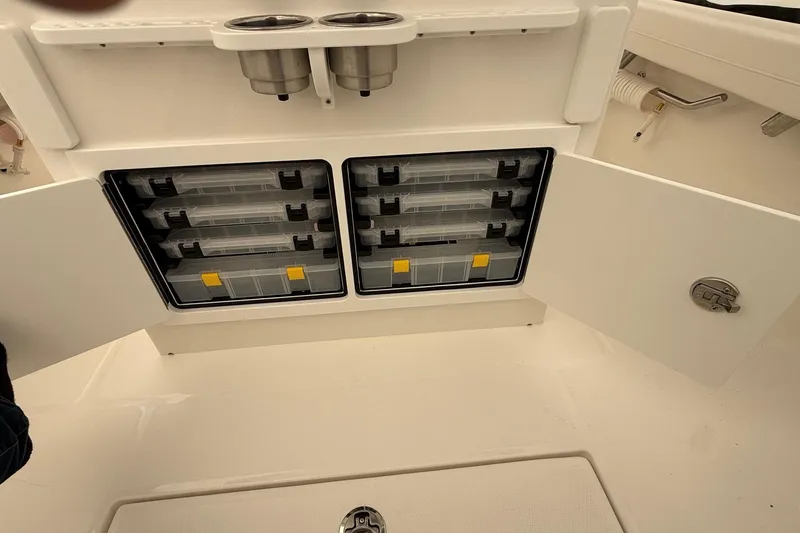 Slide: The Image of 2026 Regulator 23 boat storage compartment with organized tackle boxes and cup holders. - 50