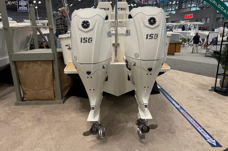 Slide: The Image of 2026 Regulator 23 boat with twin 150 horsepower outboard engines displayed indoors. - 7