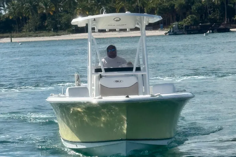Slide: The Image of 2013 Sea Hunt Ultra 234 boat cruising on clear blue water near a tropical shoreline. - 3