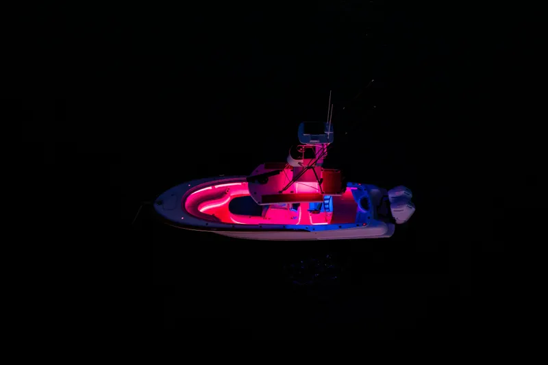 Slide: The Image of 2019 Mag Bay 33 CC boat illuminated with vibrant pink and blue lights at night. - 17