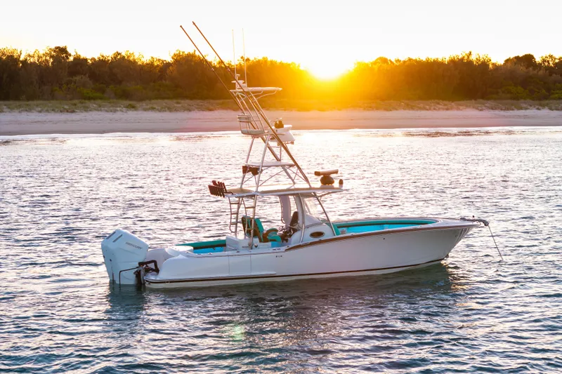 Slide: The Image of 2019 Mag Bay 33 CC boat on water at sunset, near a sandy shore. - 2