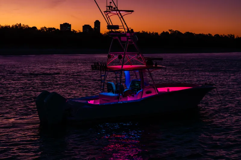 Slide: The Image of 2019 Mag Bay 33 CC boat illuminated at sunset with vibrant pink and blue lights. - 20