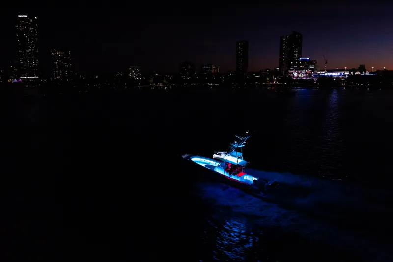 Slide: The Image of 2019 Mag Bay 33 CC boat illuminated at night, city skyline in background. - 21