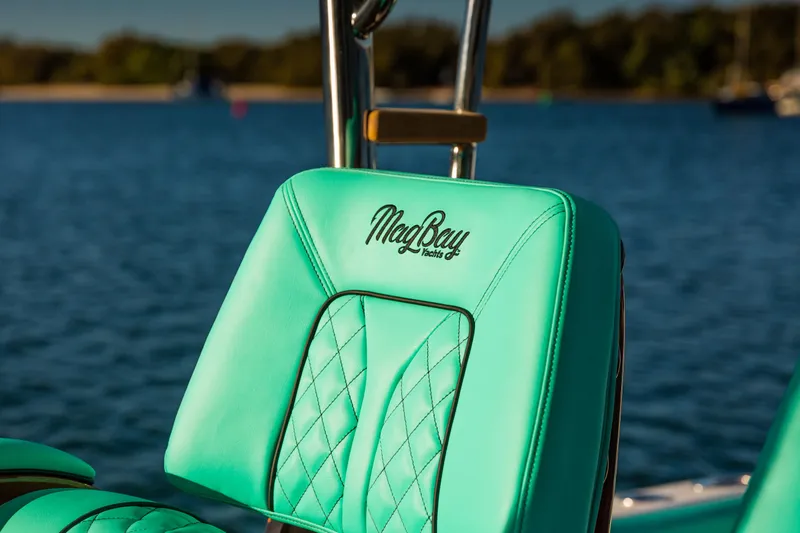 Slide: The Image of Teal seat on 2019 Mag Bay 33 CC boat, with logo, against a serene water backdrop. - 69