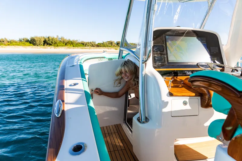 Slide: The Image of 2019 Mag Bay 33 CC boat on water, featuring a smiling person near the helm. - 83